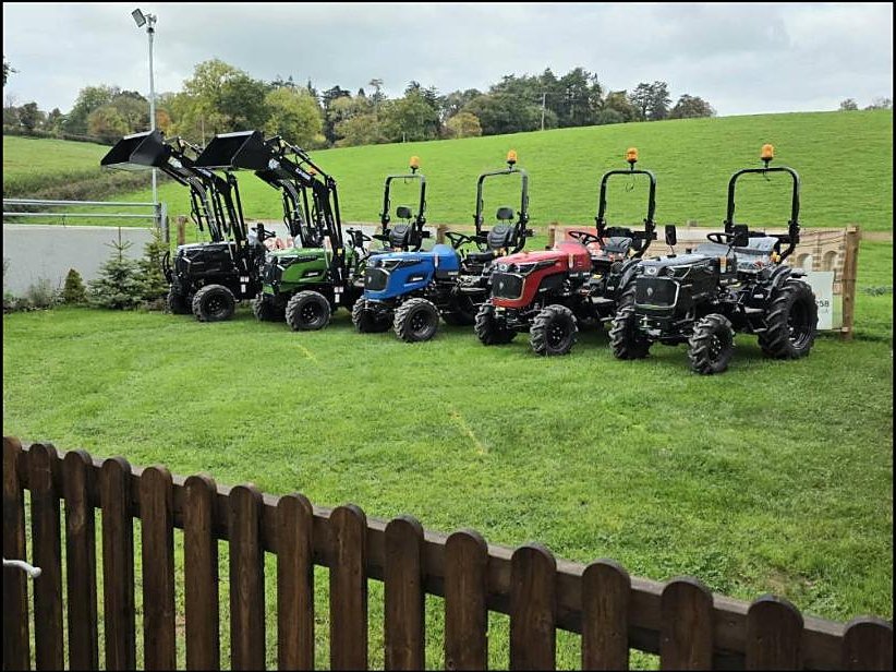 A colourful lineup of compact tractors behind the garden fence