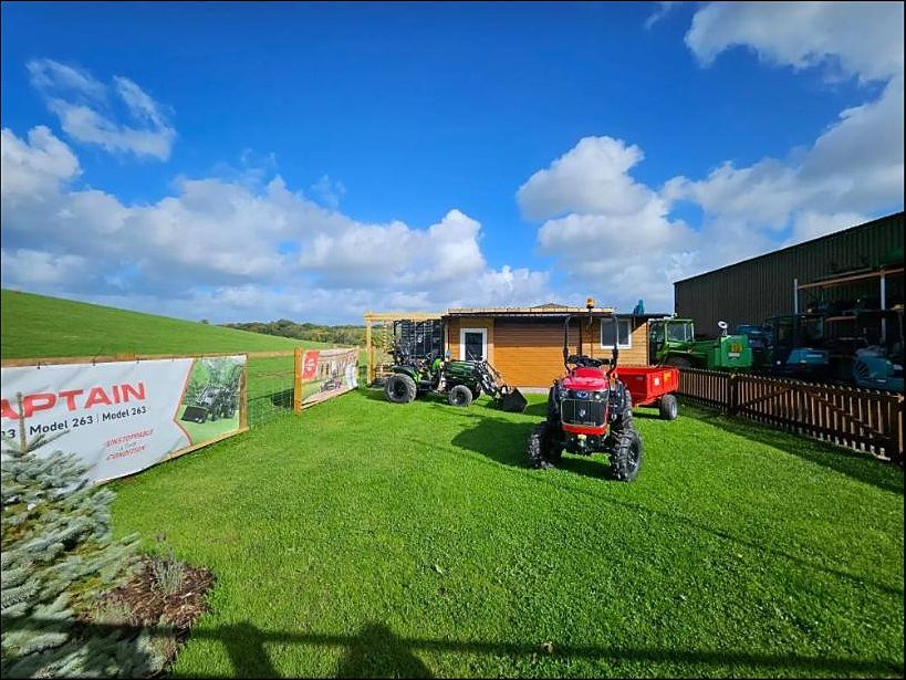 The Tractor Shed at AMIA House with compact tractors lined up on the lawn under a blue Devon sky